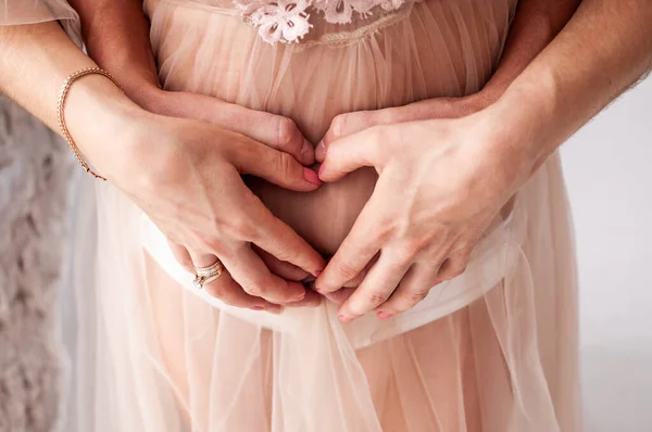 Hombre y mujer tomados de la mano en el vientre embarazada —  Fotos de Stock