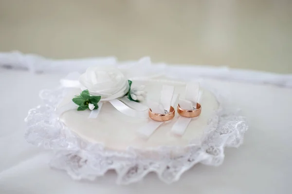 Un par de anillos de boda de oro en la almohadilla blanca —  Fotos de Stock