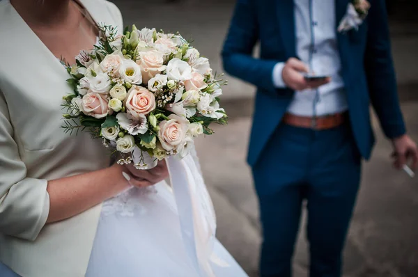 Bouquet de fleurs colorées dans la main de la mariée et du marié sur le fond — Photo