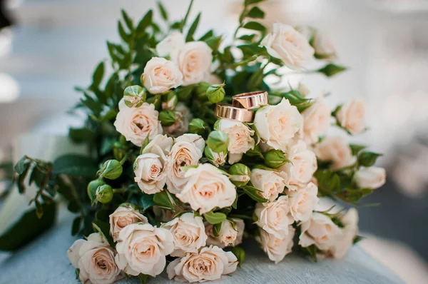 Guld vigselringar på rosa bukett blommor — Stockfoto