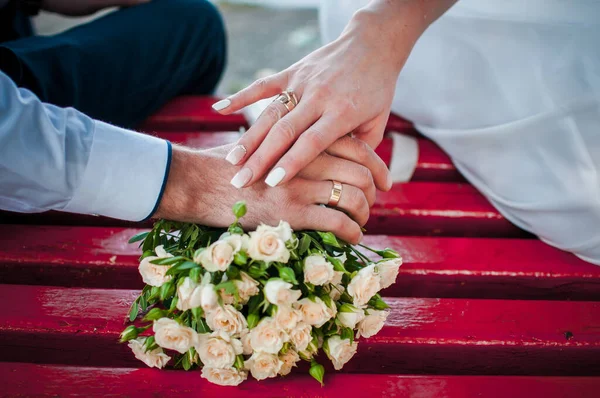 Sposa e sposo mani con mazzo di fiori sul tavolo — Foto Stock