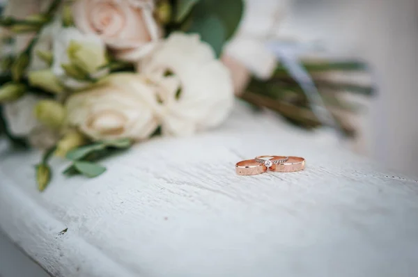 Tre gifteringer i gull på hvit marmor med blomster – stockfoto