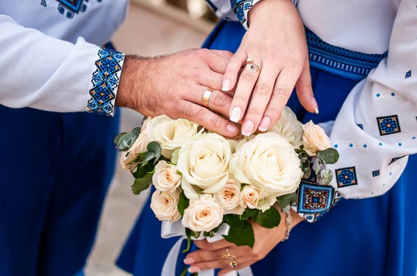 Noivo e noiva de mãos dadas no buquê de flores — Fotografia de Stock