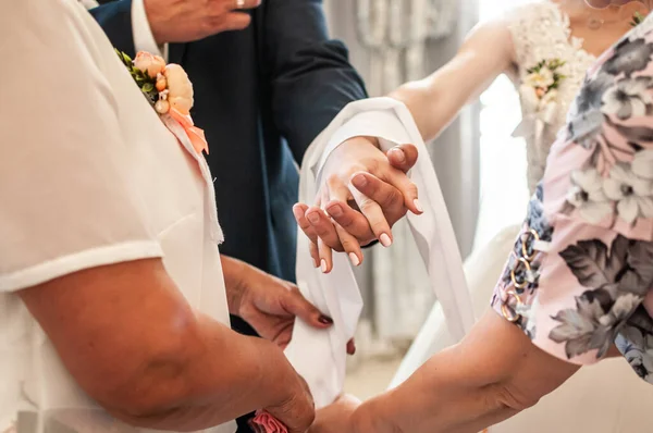 Womans tie a towel on the hands of the newlyweds