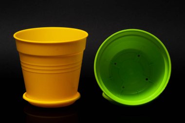 Siyah arka planda duran sarı ve yeşil bir saksı.