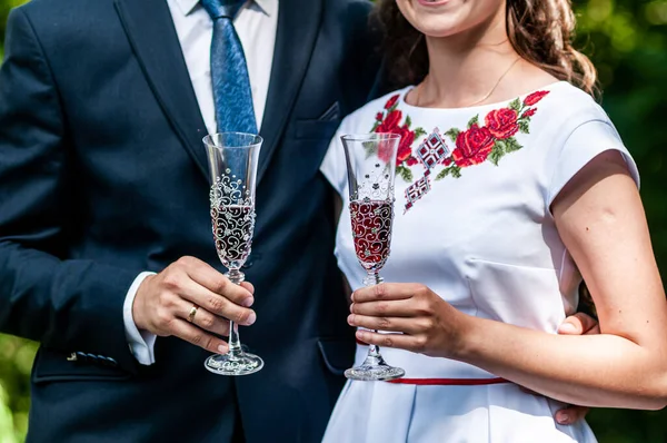 Glasses of red champagne in the hands of the newlyweds — Stock Photo, Image