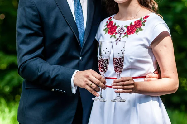 Окуляри червоного шампанського в руках молодят — стокове фото