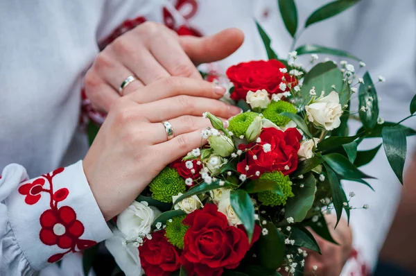 結婚式の花束の上に結婚指輪と新婚旅行の手 — ストック写真