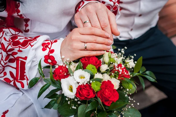 結婚式の花束の上に結婚指輪と新婚旅行の手 — ストック写真