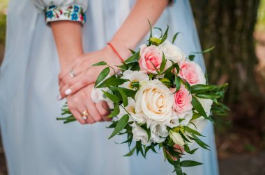 Beyaz ve pembe güllerin gelininin ellerinde düğün buketi
