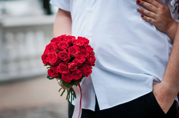 bouquet with red roses in the hands of the groom