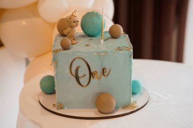 Tek boynuzlu at temalı şirin bir ilk doğum günü pastası mavi kare şekerleme, bir tepsi, sevimli bir oyuncak ayı figürü ve renkli kurabiyeler içerir. Parti tasvirleri için mükemmeldir.