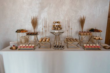 Düğünler, partiler ya da özel durumlar için mercanlar, çikolatalar, taze meyveler ve altın katmanlı mumların yer aldığı güzel düzenlenmiş tatlı büfesi.
