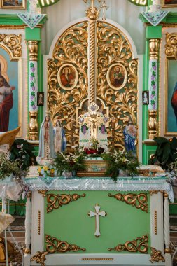 Zengin dekore edilmiş bir Katolik kilise sunağında dini simgeler, Bakire Meryem ve İsa heykelleri ve kutsal bir atmosfer yaratan canlı çiçek düzenlemeleri yer alıyor.