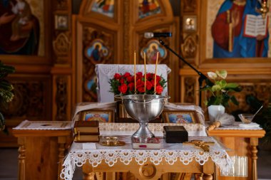 Doğu Ortodoks kilisesindeki zengin dekore edilmiş bir sunakta kırmızı güller, mumlar ve dini ikonlar içeren gümüş bir sunak serinletici bir ruh hali uyandırıyor.