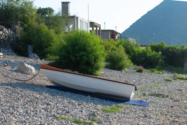 Skadar Gölü 'nün kayalık kıyısında, içi turuncu ve beyaz olan plastik bir tekne.
