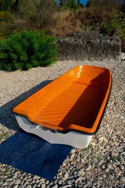 Skadar Gölü 'nün kayalık kıyısında, içi turuncu ve beyaz olan plastik bir tekne.