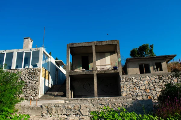 Bitmemiş beton ev dik bir Skadar Gölü üzerine tünemiş engebeli suların ortasında eğimli bir mimari..