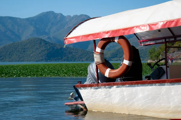 Yamaha F6CMHL dış teknesi ve bir cankurtaran şamandırası, dağlara karşı ve sakin bir su yüzeyine karşı. Karadağ, Skadar Gölü, 13 Ağustos 2025