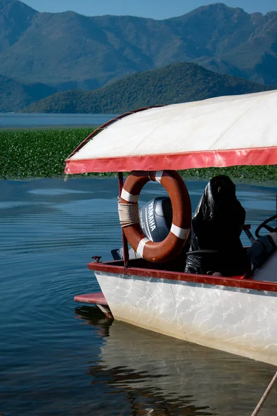 Yamaha F6CMHL dış teknesi ve bir cankurtaran şamandırası, dağlara karşı ve sakin bir su yüzeyine karşı. Karadağ, Skadar Gölü, 13 Ağustos 2025