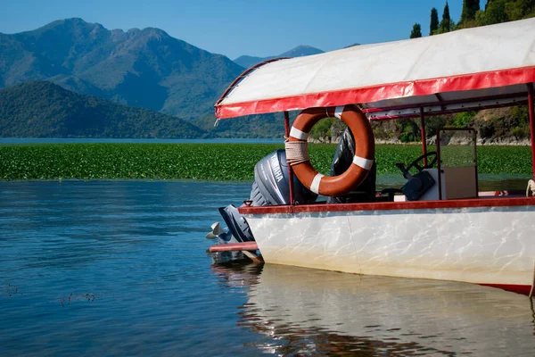 Yamaha F6CMHL dış teknesi ve bir cankurtaran şamandırası, dağlara karşı ve sakin bir su yüzeyine karşı. Karadağ, Skadar Gölü, 13 Ağustos 2025