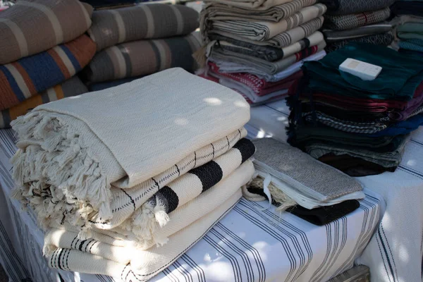 Görüntü, bir el sanatları festivalinde sergilenen Türk peshtemal havlusunu gösteriyor. Geleneksel tekstil işçiliği, parlak renkleri ve piyasa tarzı atmosferi olan bir aile şirketini vurguluyor.