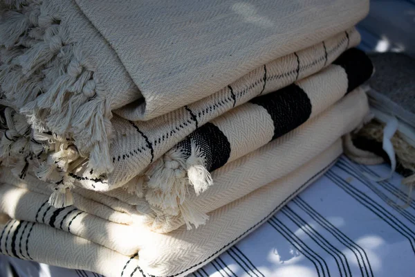 Görüntü, bir el sanatları festivalinde sergilenen Türk peshtemal havlusunu gösteriyor. Geleneksel tekstil işçiliği, parlak renkleri ve piyasa tarzı atmosferi olan bir aile şirketini vurguluyor.