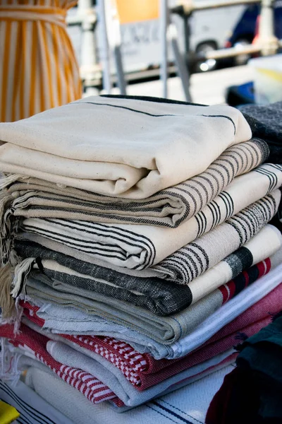 Görüntü, bir el sanatları festivalinde sergilenen Türk peshtemal havlusunu gösteriyor. Geleneksel tekstil işçiliği, parlak renkleri ve piyasa tarzı atmosferi olan bir aile şirketini vurguluyor.