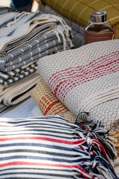 Görüntü, bir el sanatları festivalinde sergilenen Türk peshtemal havlusunu gösteriyor. Geleneksel tekstil işçiliği, parlak renkleri ve piyasa tarzı atmosferi olan bir aile şirketini vurguluyor.