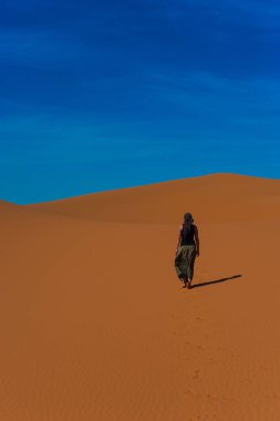 Girl walk in Erg Chebbi Desert, Sahara Desert near Merzouga, Morocco clipart
