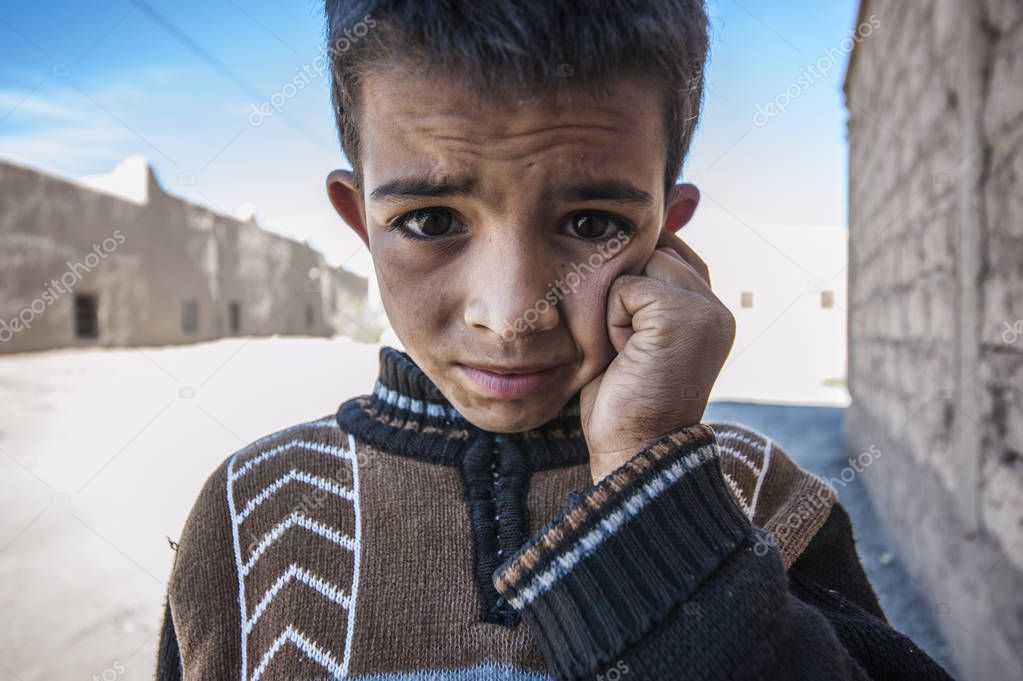 Portrait of a boy looking up at the camera in village Merzouga, Morocco