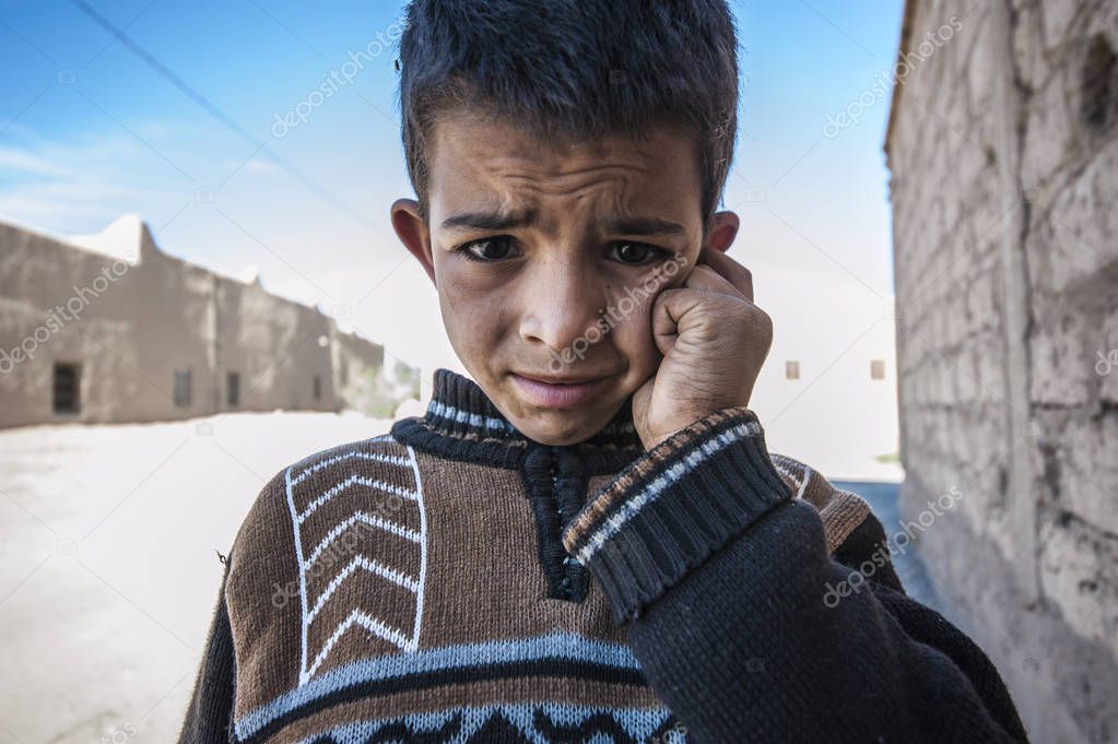 Portrait of a boy looking up at the camera in village Merzouga, Morocco