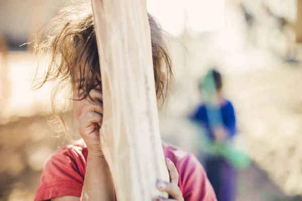 Kız bir ahşap direğin arkasına gizler