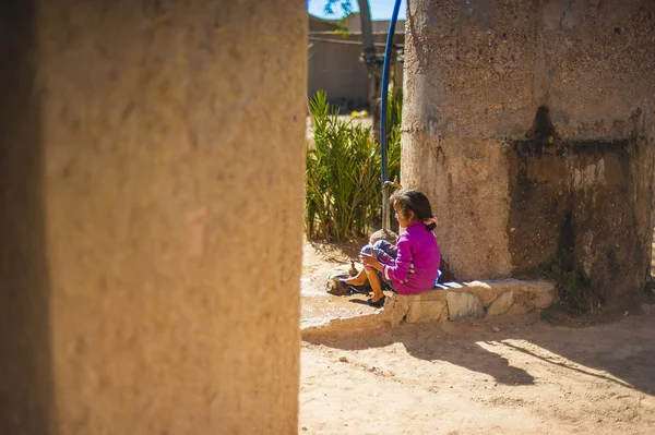 Girl sitting in front of her house in Merzouga, Morocco