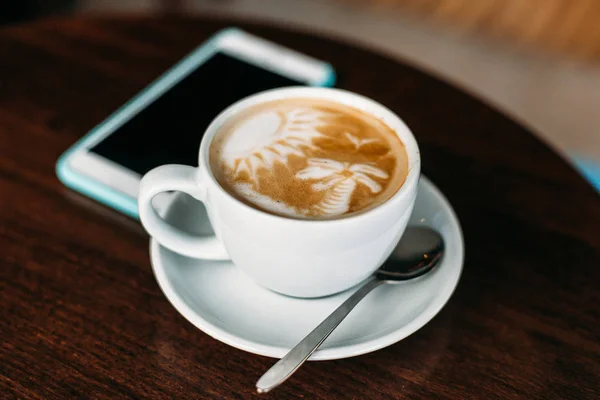 Tahta masada bir fincan sıcak latte sanat kahvesi.