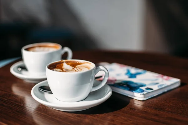 iki fincan cappuccino latte art ahşap masa Tarih ile.