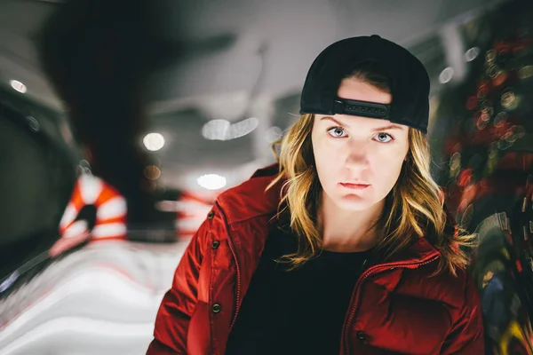 Dalgın yüzü şık şapkası kırmızı ceketli trendy çekici kız. Arka plan üzerinde yanlış camdır