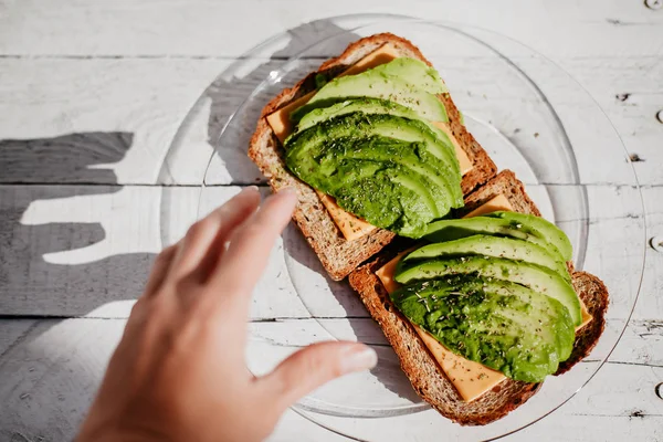 Avokado, peynir ve otlar ile tam buğday tost. Yararlı bir lezzetli breakfast.