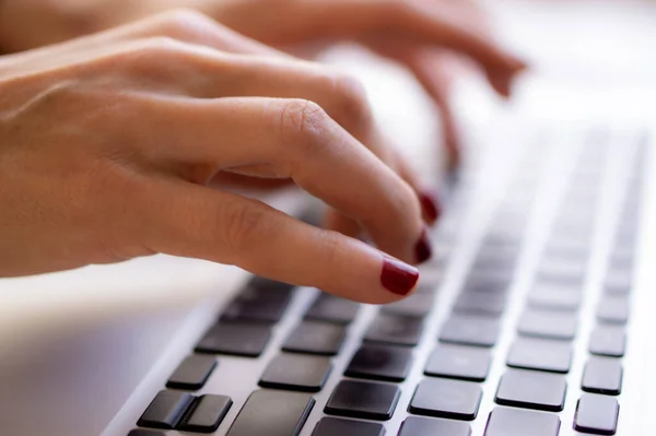 Genç bir kadın dizlerinin üstünde dizlerinin üstünde yatak odasındaki yatakta çalışıyor. Evde çalışıyorum..