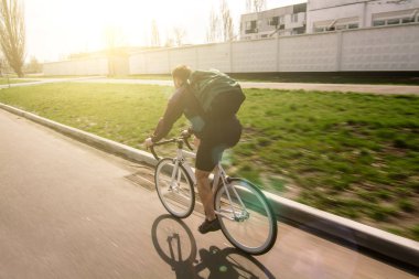 Bir bisikletçi binmek çanta bisikletiyle günbatımı arka plan üzerinde