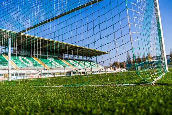 Football goal net  with little tribune on background and colorful grass and sky