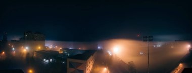 Sis gece panorama sokak ışık, futbol stadyumu ve karanlık gökyüzü ile çok