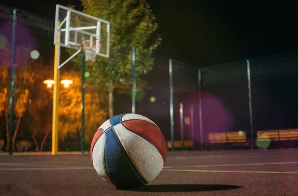 Derma Basketbol topuyla sepeti ve arka plan üzerinde parlayan ışıkla alacakaranlıkta kırmızı alan net