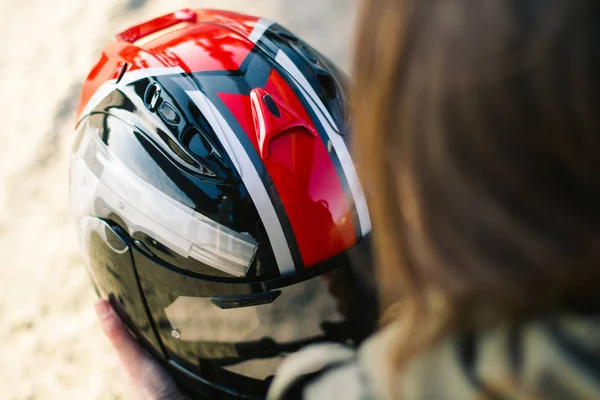 Pretty girl with custom motorcycle helmet in hands with sunbright background