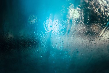 Alacakaranlık ve bokeh ışıklar araba yan camının su damlaları