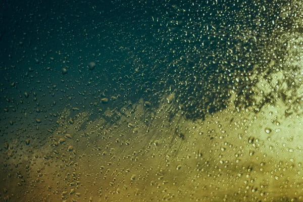 Alacakaranlık ve bokeh ışıklar araba yan camının su damlaları
