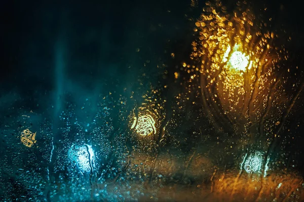 Water drops on car side glass in dusk and bokeh lights