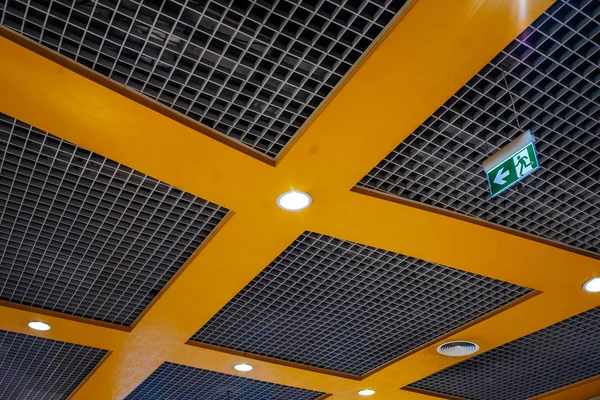 Orange grid structure of suspended ceiling in an mall building. Abstract modern architecture. Generic image of contemporary interior design. Geometric composition with square shape. Light installed.