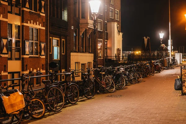 夜晚舒适的阿姆斯特丹街道，有自行车停车场和温暖的光线 — 图库照片