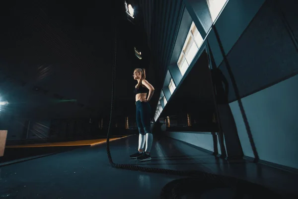 Full length wide angle shot of a woman performing rope climbs at